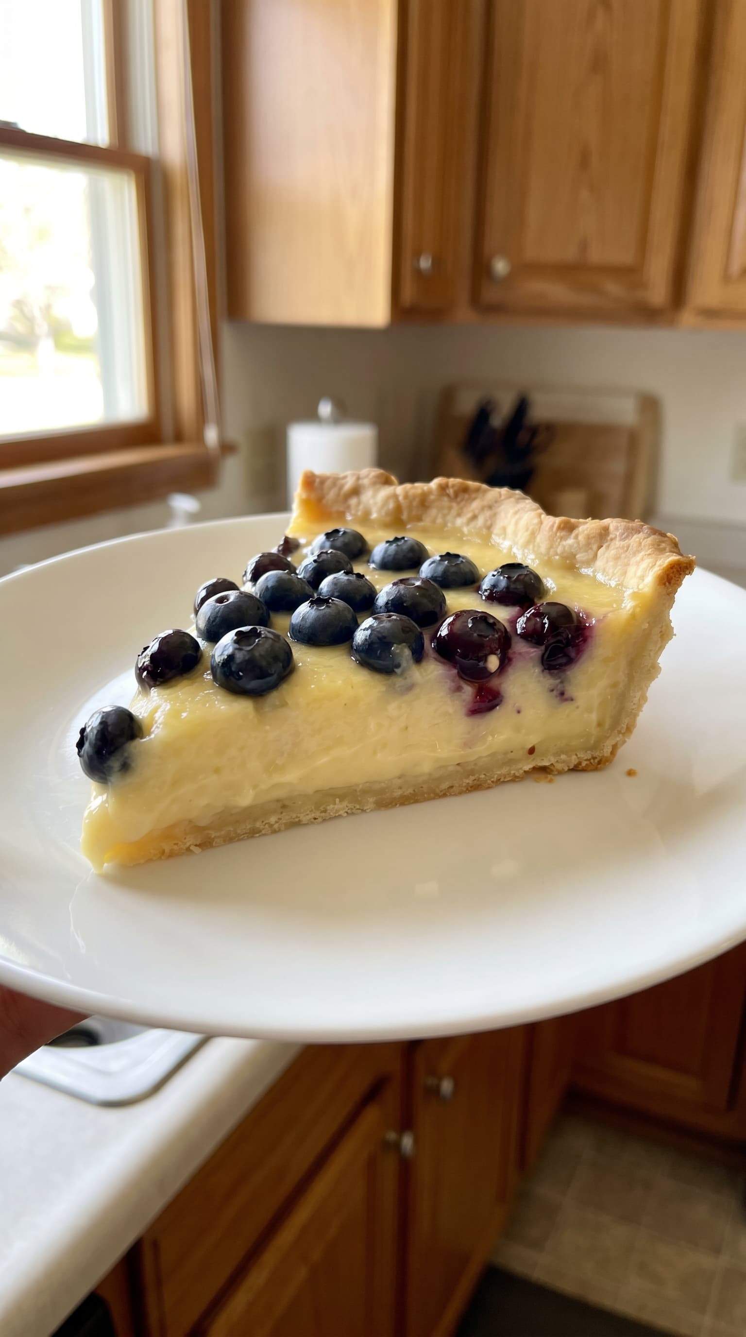 A lemon blueberry tart topped with fresh blueberries on a serving plate.